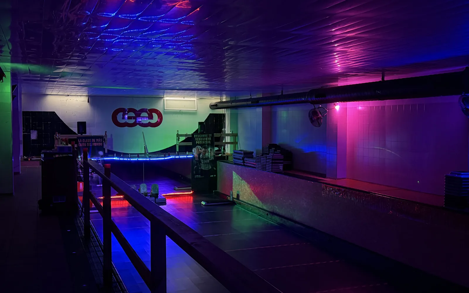 La sala d'activitats amb els llums de colors encesos: l'escenari, les baranes i el logo del CEEC a la paret del fons